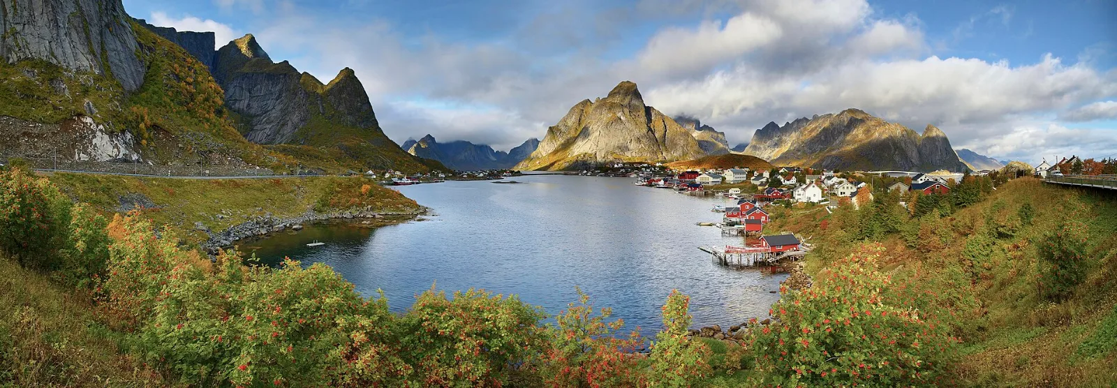 Das Fischerdorf Reine mit Holzhäusern vor steilen Bergen auf den Lofoten